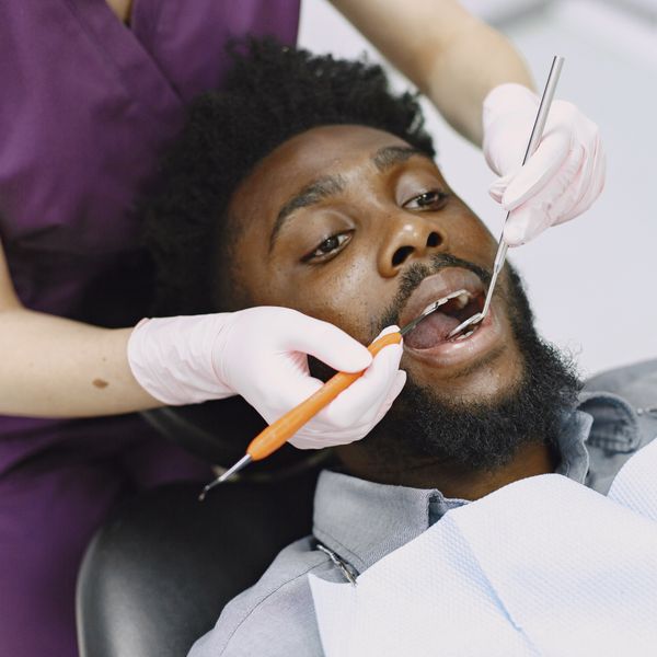 Dentist examining a man's teeth during a routine dental checkup.