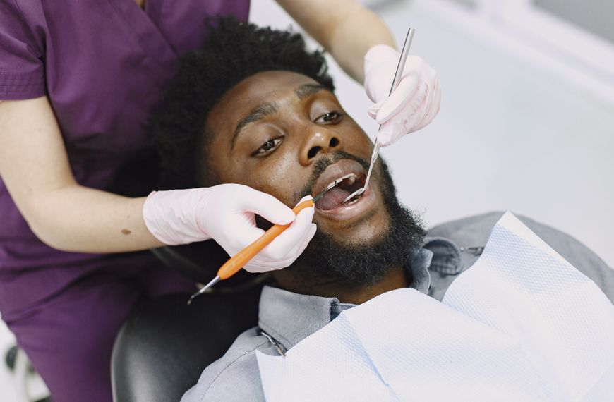 Dentist examining a man's teeth during a routine dental checkup.