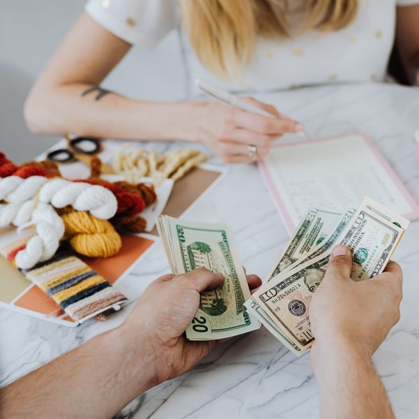 Two people handling cash and budgeting with a calculator and notebook at a table.
